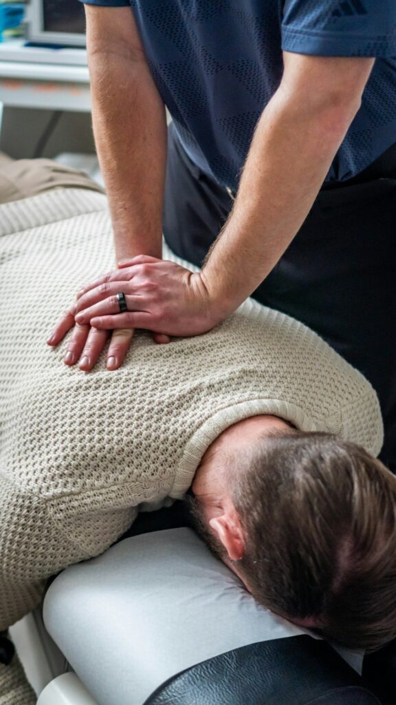 Person seated at home applying a wrapped cold pack to the neck after a vehicle accident.